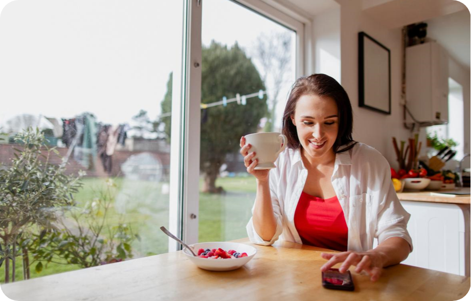 eine Frau mit einem Kaffee und ihrem Mobiltelefon